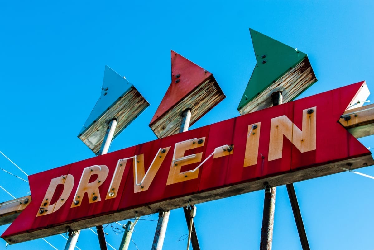 Red drive in theater sign against blue sky